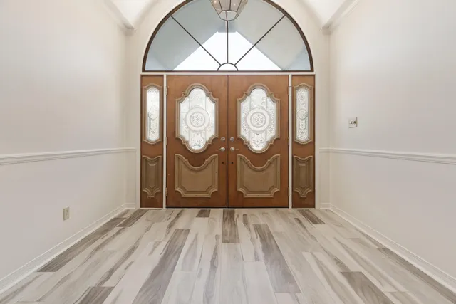 a spacious bedroom with a bed a chandelier and large window
