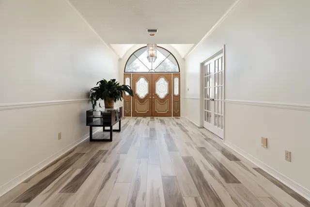 a spacious bedroom with a bed a dresser and a chandelier