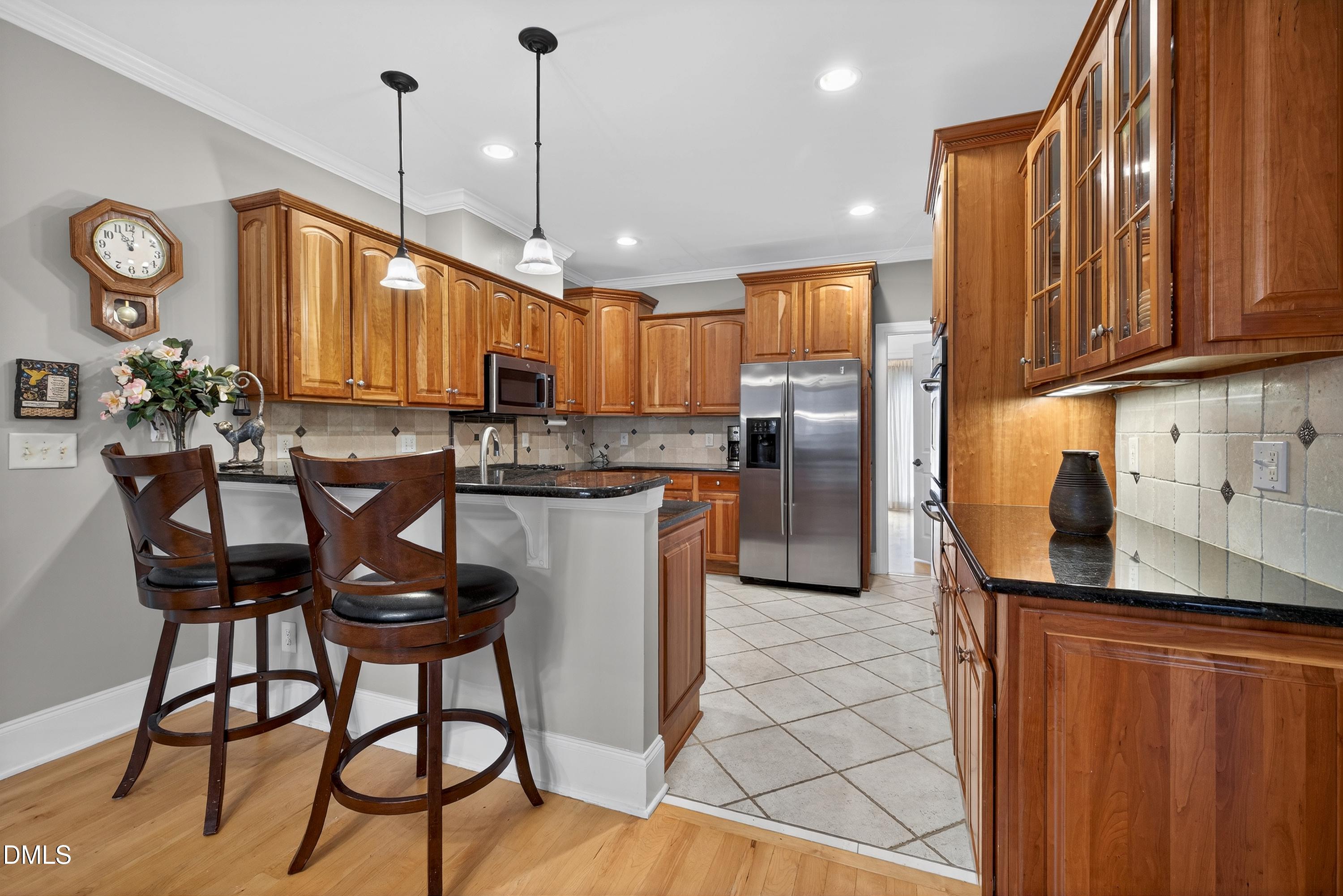 4613 Cross Brook Lane Raleigh, NC 27610 - Photo 19 of 53 a kitchen with stainless steel appliances kitchen island granite countertop a refrigerator a stove a sink with island chairs and wooden cabinets