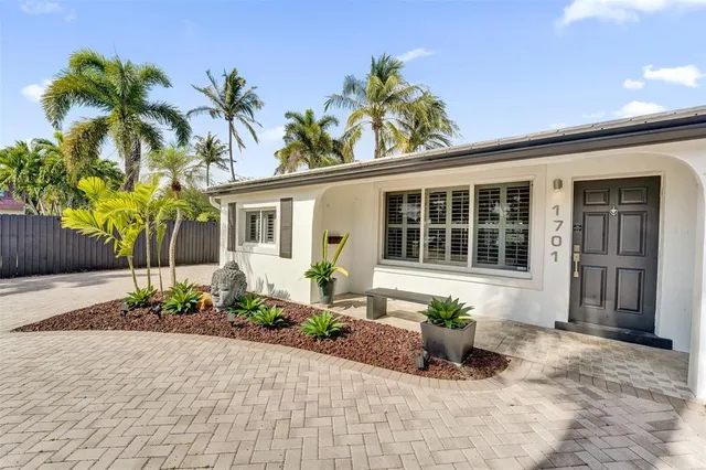 a front view of a house with a garden and potted plants