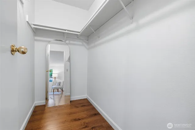 a view of a hallway with wooden floor and a bathroom