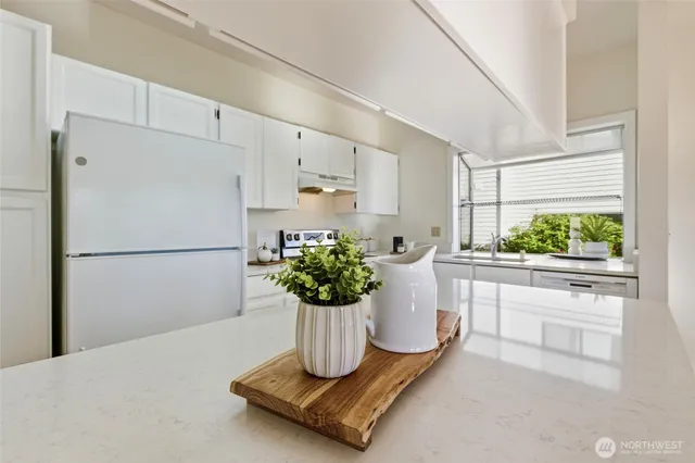 a kitchen with a refrigerator a stove a window and white cabinets