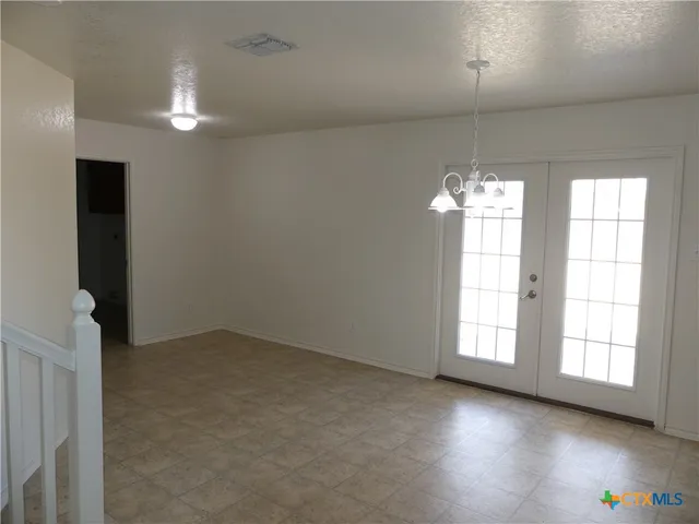 an empty room with chandelier fan and windows