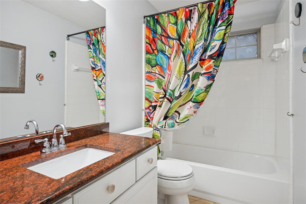 125 Bricknell Lane Coppell, TX 75019 - Photo 25 of 27 a bathroom with a granite countertop sink a toilet and a shower curtain