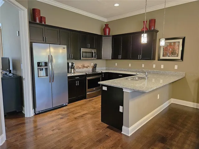 a kitchen with granite countertop a refrigerator a sink a stove a microwave and wooden cabinets