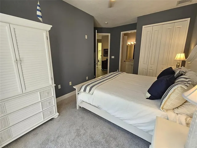 a bedroom with a bed chair and two large window