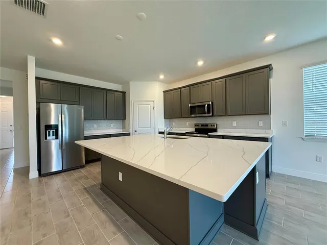 a view of kitchen with kitchen island and stainless steel appliances