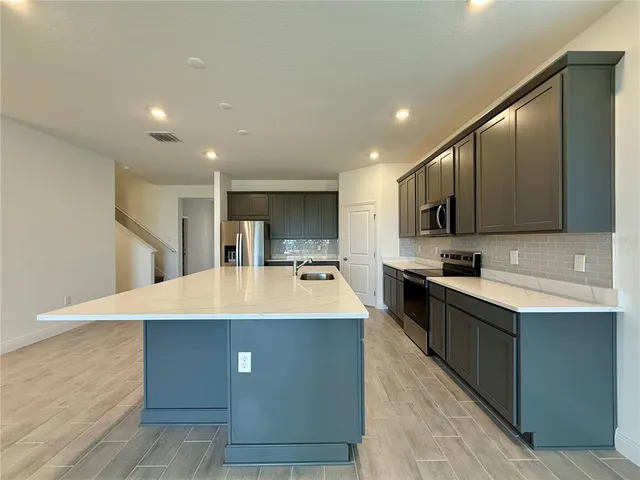 a view of kitchen with kitchen island and stainless steel appliances