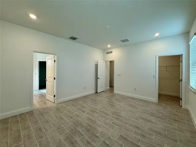 an empty room with wooden floor and windows