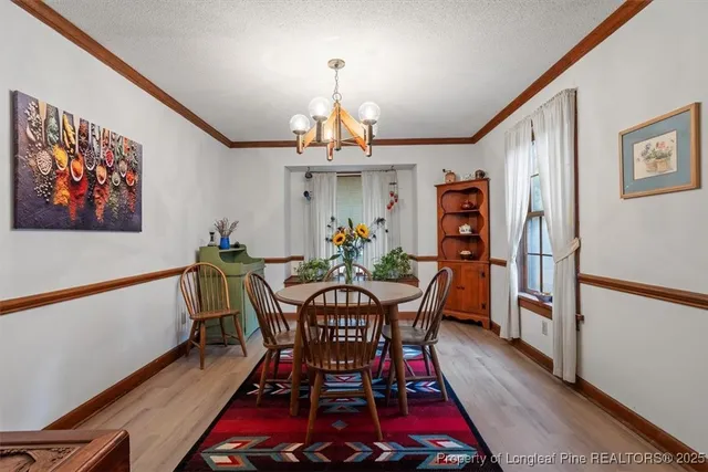a view of a dining room with furniture a chandelier and wooden floor
