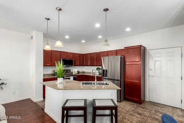 a kitchen with stainless steel appliances a dining table chairs refrigerator and microwave