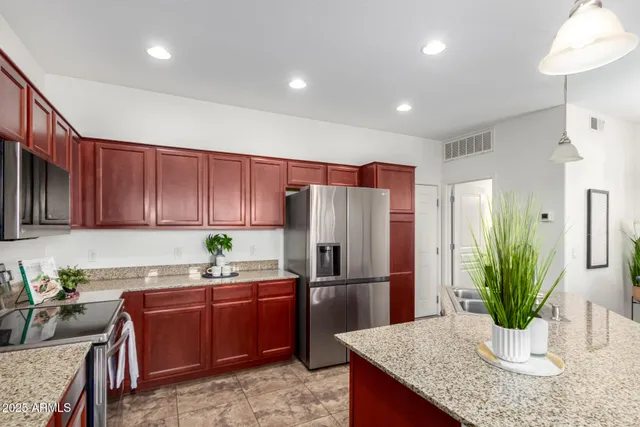 a kitchen with granite countertop a refrigerator a stove and a cabinets