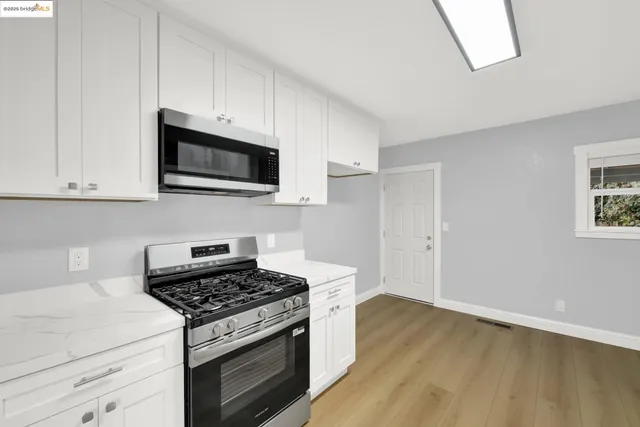 a kitchen with stainless steel appliances a white cabinet and a stove top oven
