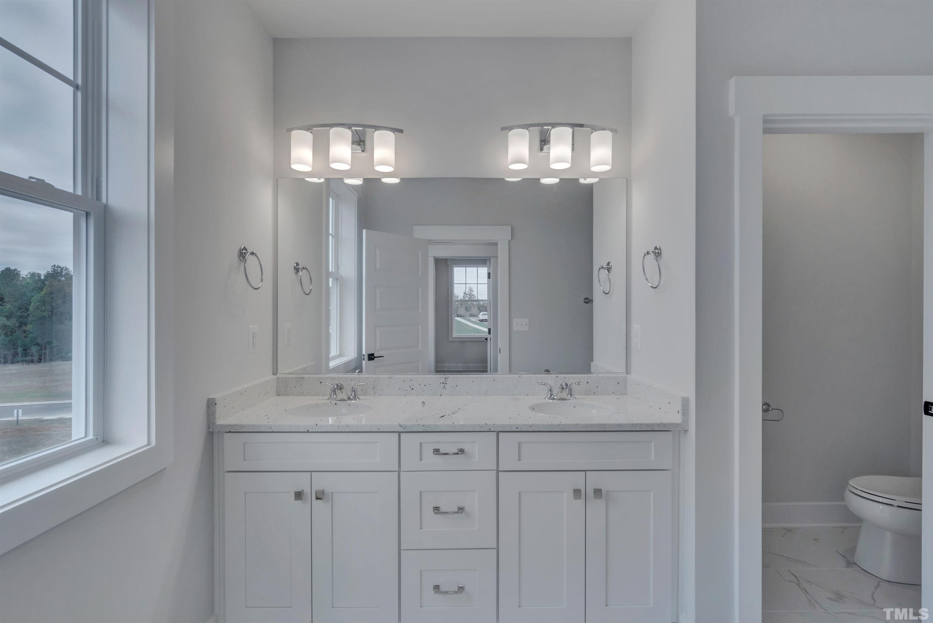 167 Dunloe Loop Raleigh, NC 27603 - Photo 8 of 16 a bathroom with double vanity and a mirror