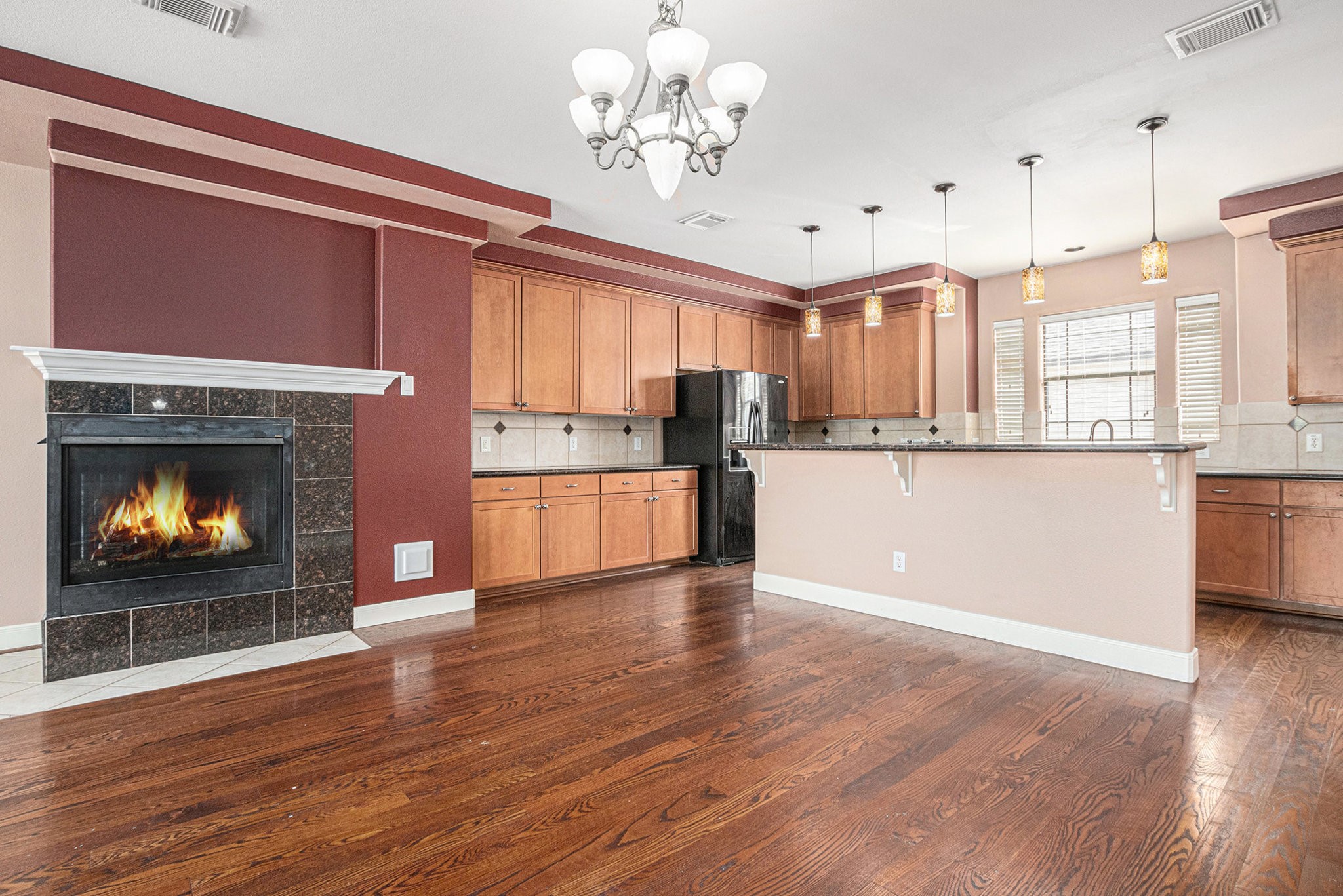 2402 Calumet Street, Unit B Houston, TX 77004 - Photo 11 of 40 a open kitchen with granite countertop a stove top oven a refrigerator a fireplace with wooden floor and cabinets