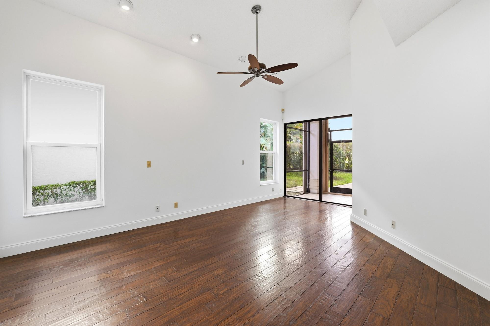 2498 Northwest 63rd Street Boca Raton, FL 33496 - Photo 13 of 39 an empty room with wooden floor chandelier fan and windows