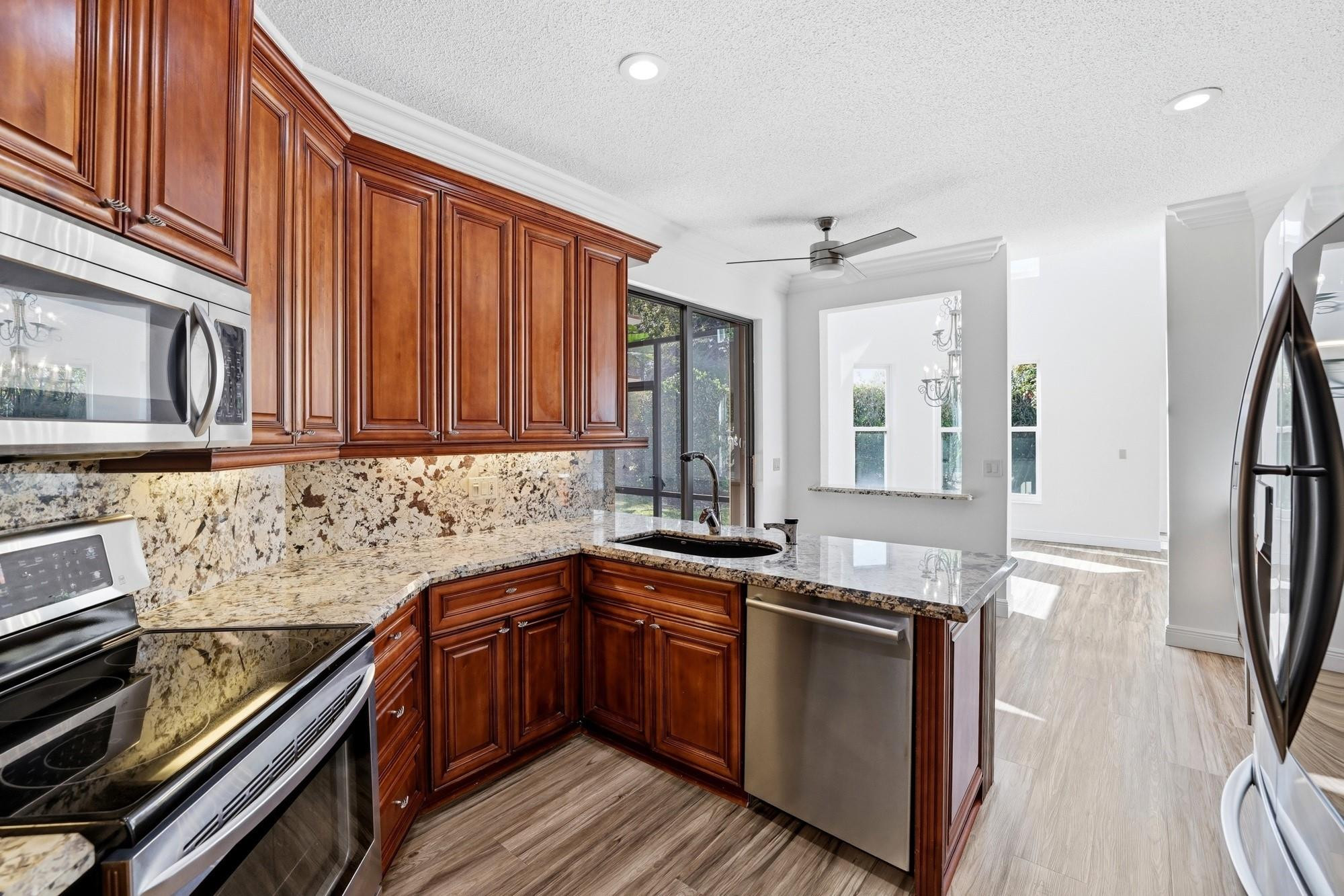 2498 Northwest 63rd Street Boca Raton, FL 33496 - Photo 8 of 39 a kitchen with granite countertop stainless steel appliances and wooden cabinets