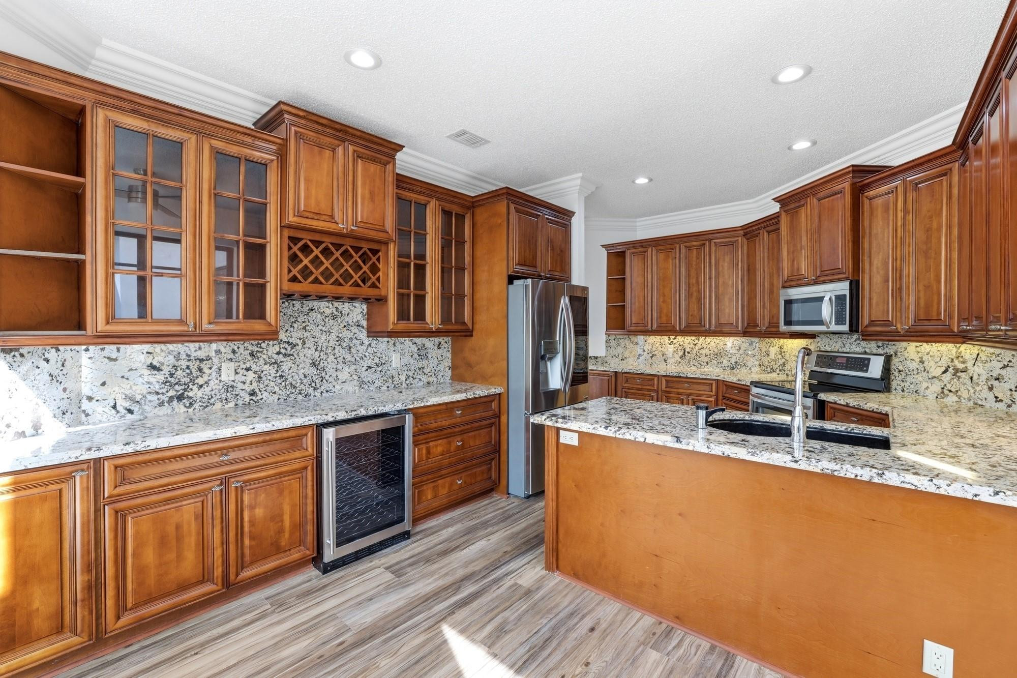 2498 Northwest 63rd Street Boca Raton, FL 33496 - Photo 10 of 39 a kitchen with stainless steel appliances granite countertop a stove a sink dishwasher a refrigerator and cabinets with wooden floor