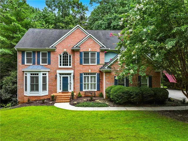 a front view of a house with a yard and green space
