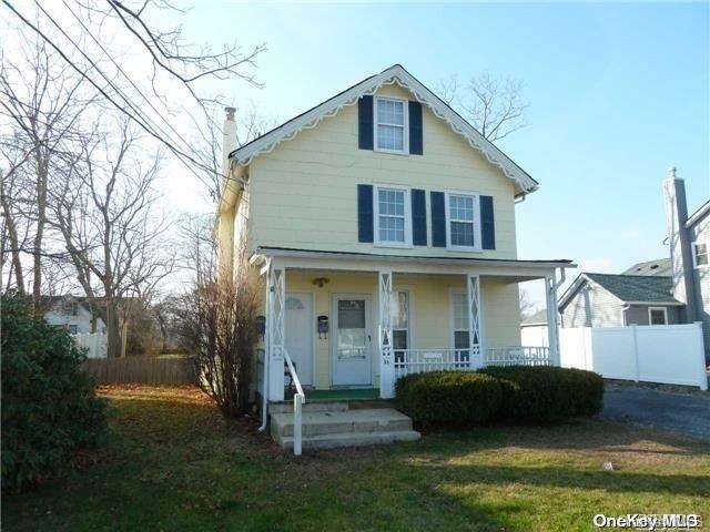 View of front of home with a front lawn, fence, a chimney, and a porch
