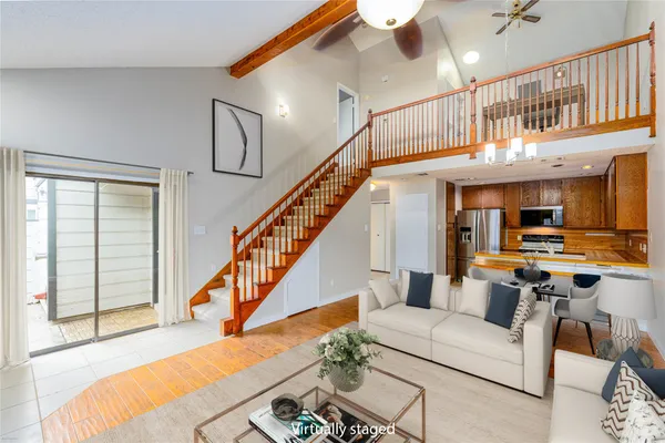 a living room with furniture kitchen view and a large window