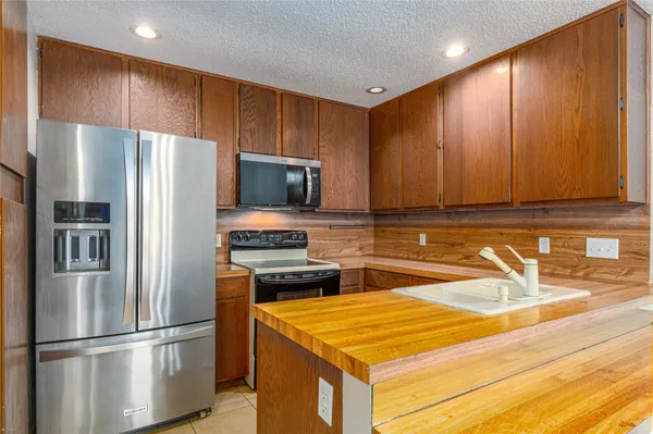 a kitchen with stainless steel appliances granite countertop a refrigerator a stove and a sink