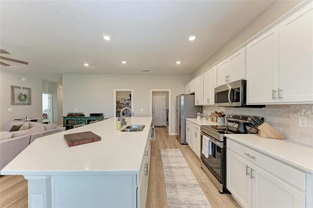 a large kitchen with kitchen island a stove a sink a refrigerator and a dining table with wooden floor