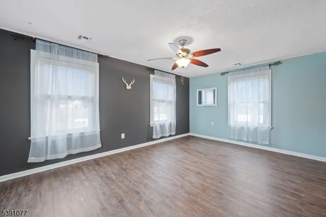 a view of an empty room with a window and wooden floor