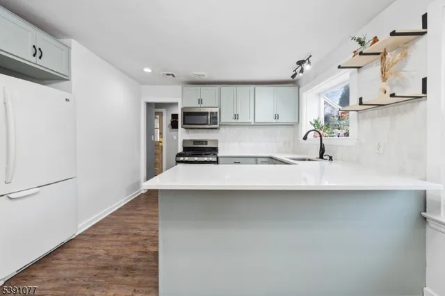 a kitchen with stainless steel appliances a sink a stove a refrigerator and cabinets