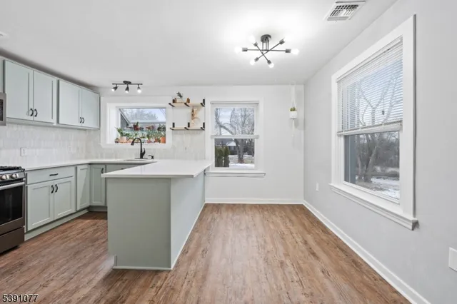 a kitchen with a wooden floors a sink dishwasher and white cabinets with wooden floor