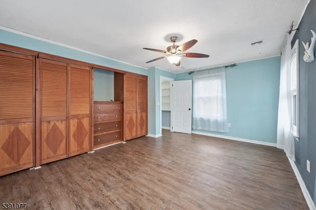 an empty room with wooden floor and ceiling fan