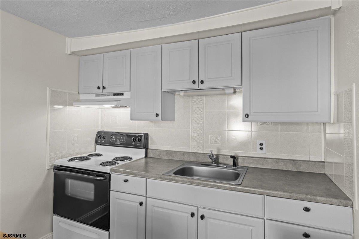 1000 West Brigantine Avenue, Unit 4 Brigantine, NJ 08203 - Photo 7 of 35 a kitchen with white cabinets and white appliances