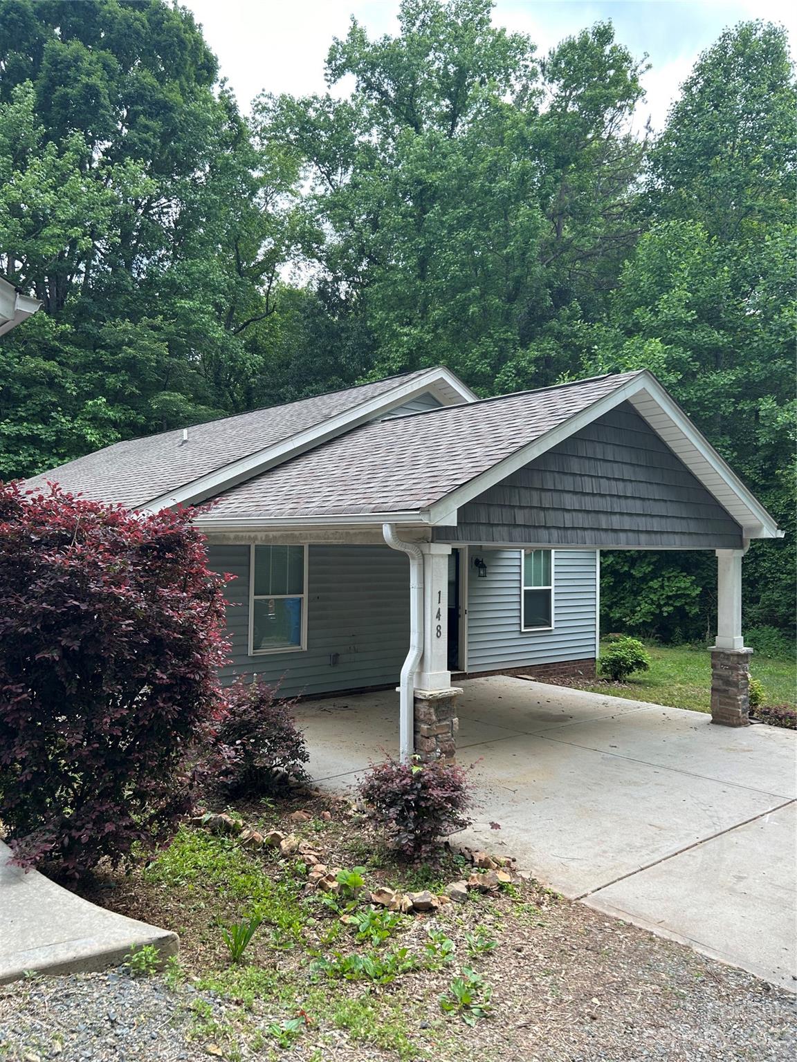 a view of a house with a yard plants and large tree