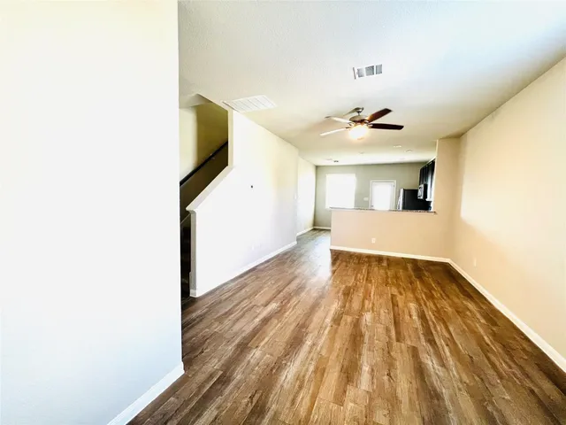 a view of a room with wooden floor and a ceiling fan
