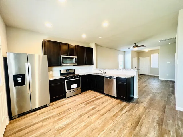 a large kitchen with a large counter top stainless steel appliances and cabinets