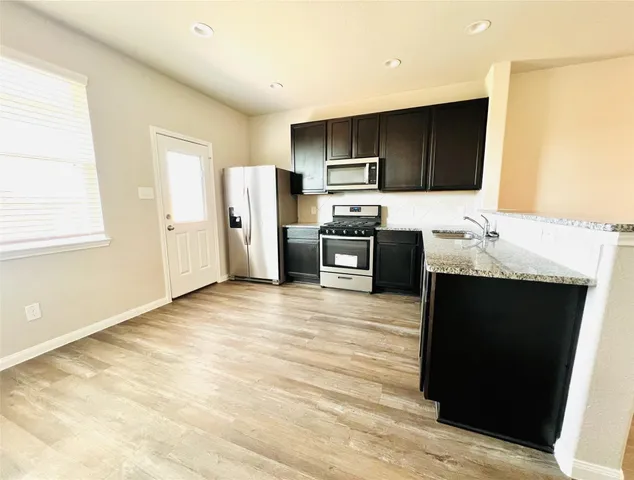 a kitchen with stainless steel appliances kitchen island granite countertop a refrigerator stove and sink