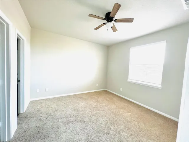 an empty room with a ceiling fan and window