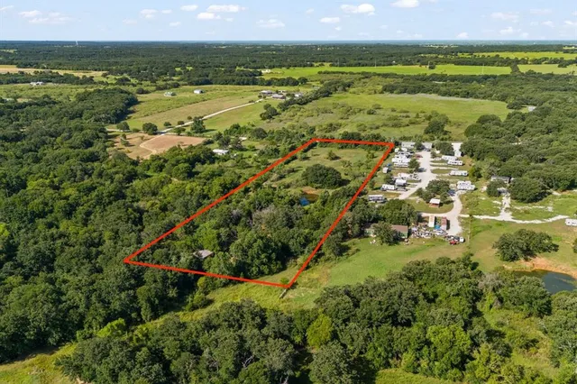 an aerial view of residential houses with outdoor space and trees
