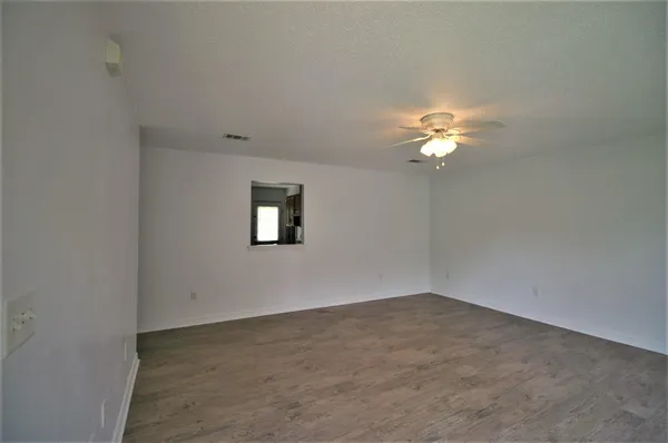 an empty room with a chandelier fan and windows