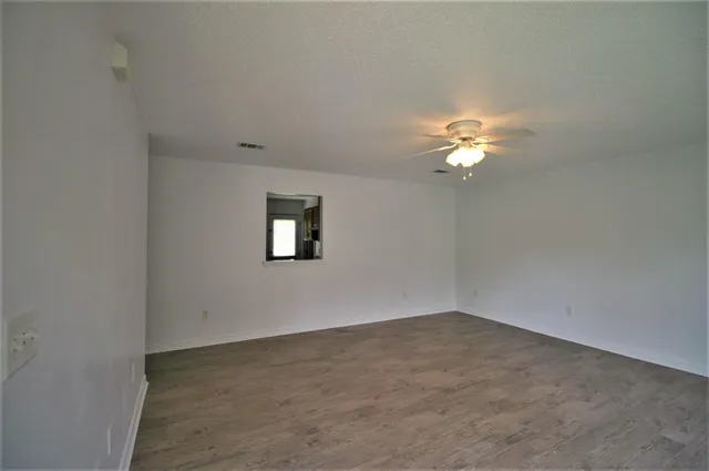 an empty room with a chandelier fan and windows