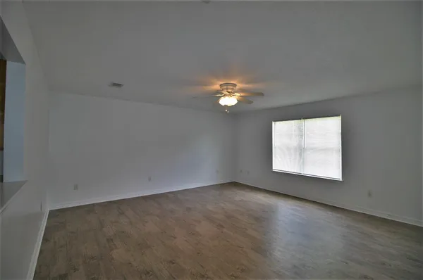 an empty room with a chandelier fan and windows