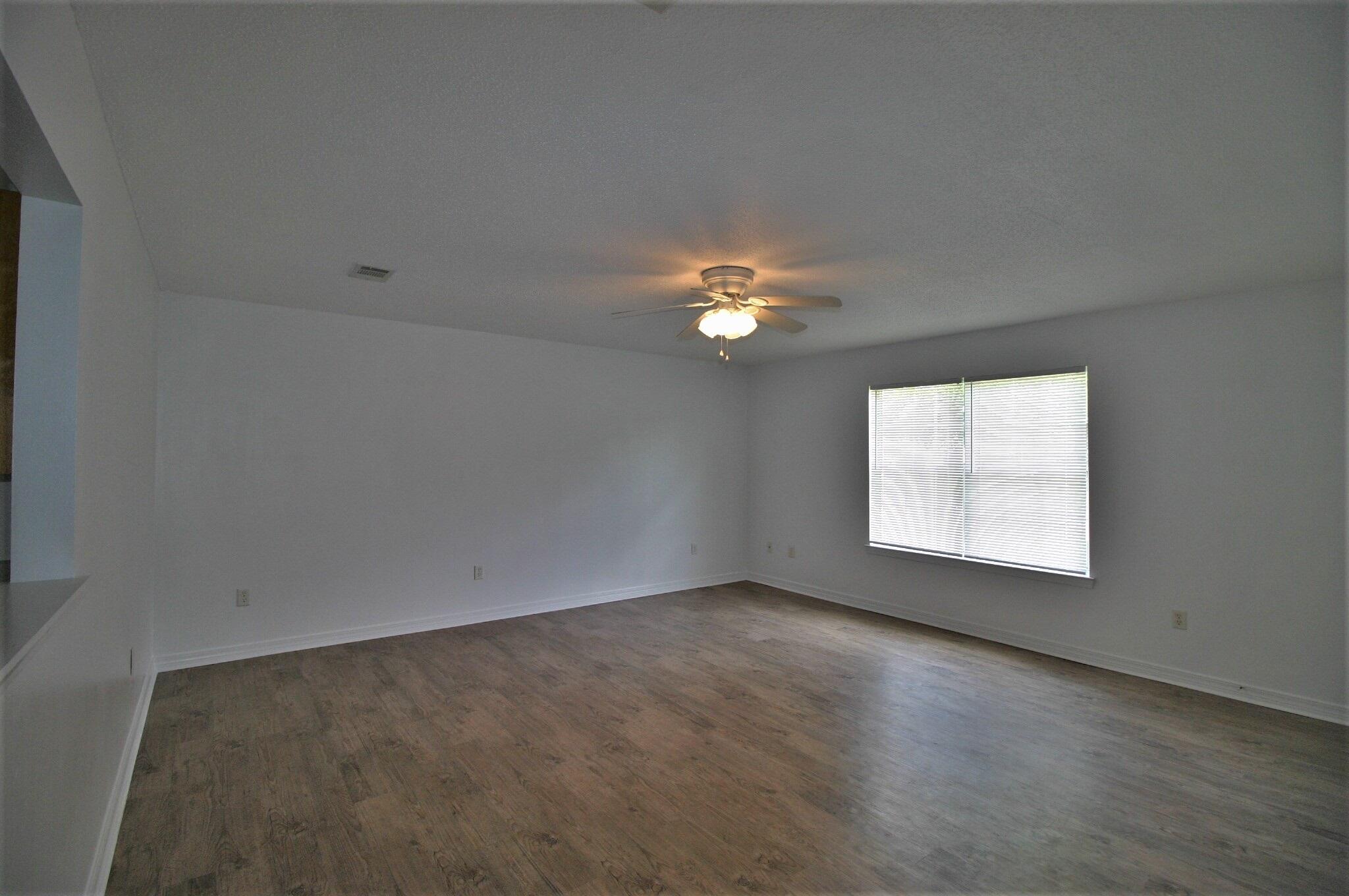 552 Brock Avenue Crestview, FL 32539 - Photo 4 of 13 an empty room with a chandelier fan and windows