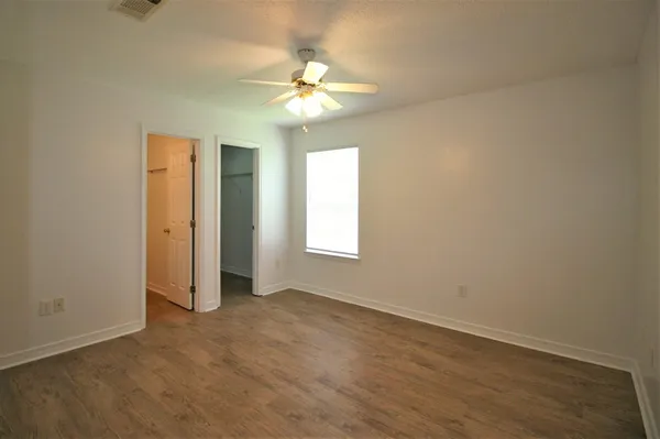 an empty room with a chandelier fan and windows