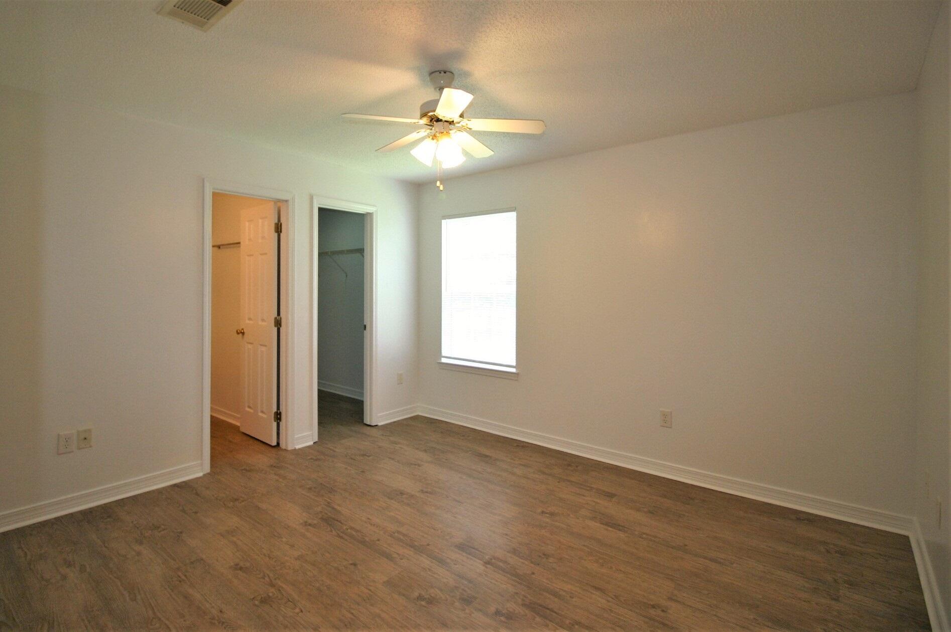 552 Brock Avenue Crestview, FL 32539 - Photo 9 of 13 an empty room with a chandelier fan and windows