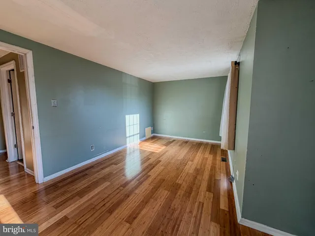an empty room with wooden floor and entrance