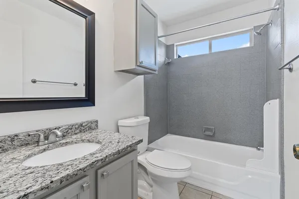 a bathroom with a granite countertop sink mirror vanity and toilet