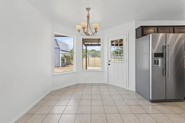 a view of an empty room with window and chandelier fan
