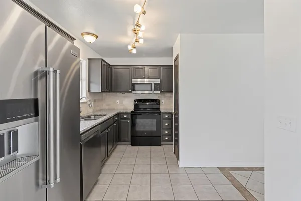 a kitchen with granite countertop a refrigerator and a stove top oven