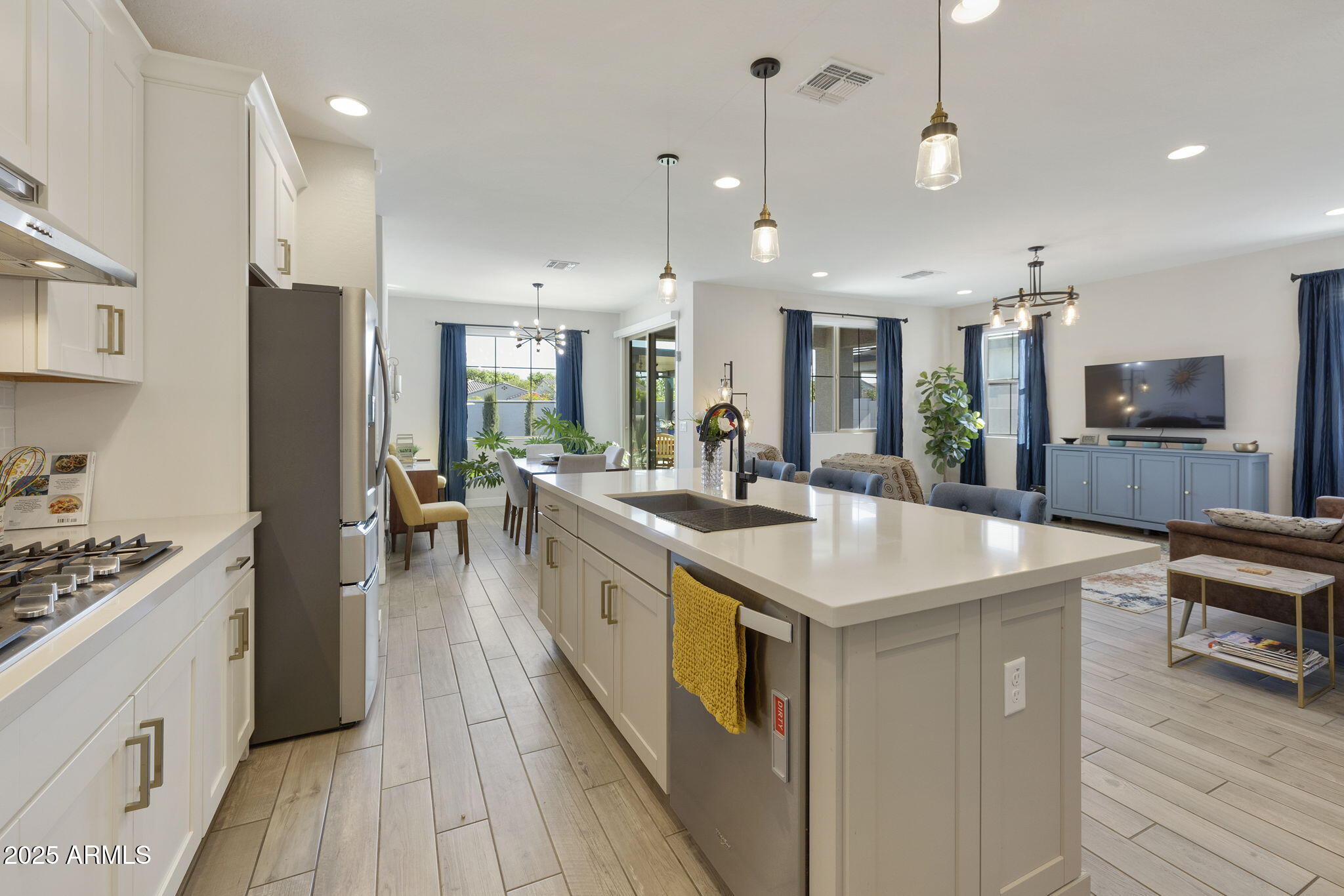4557 South Element Mesa, AZ 85212 - Photo 23 of 34 a kitchen with kitchen island a stove a sink a refrigerator and a dining table with wooden floor