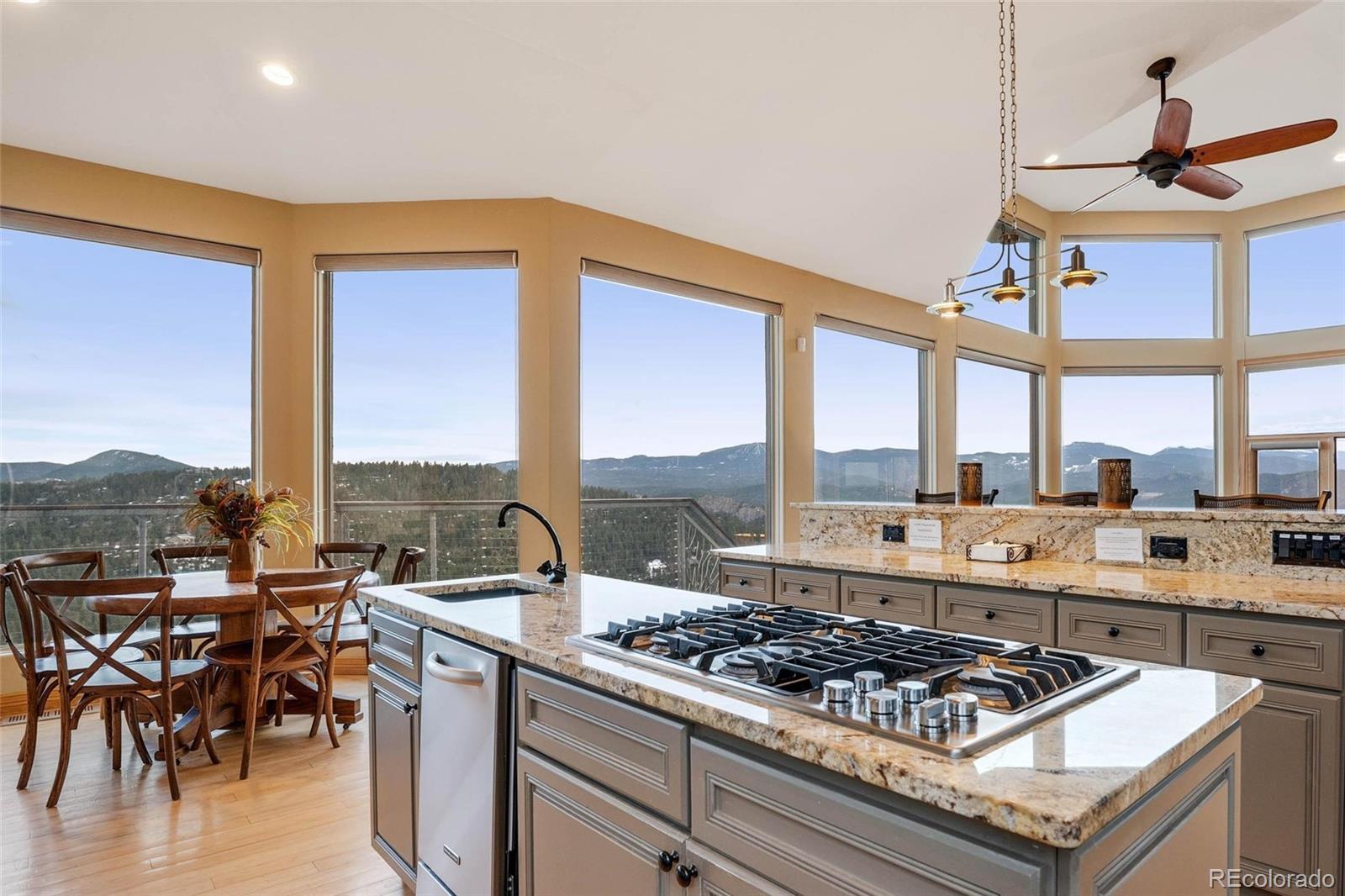 25580 Sunset Lane Evergreen, CO 80439 - Photo 12 of 40 a kitchen with a stove a sink and a dining table with wooden floor
